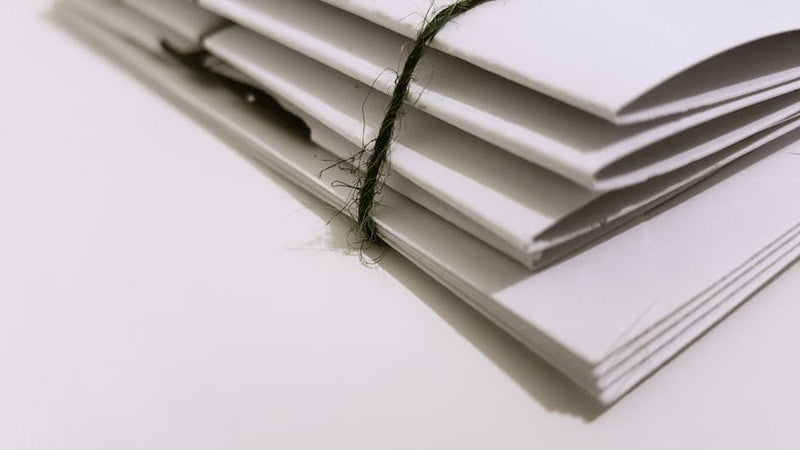 Bundle of white envelopes tied with string on a white background