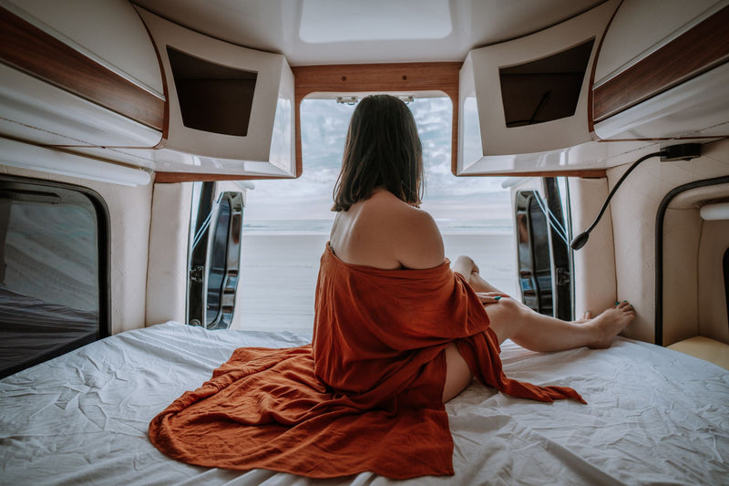 cozy camper van interior with a made bed facing an open rear door
