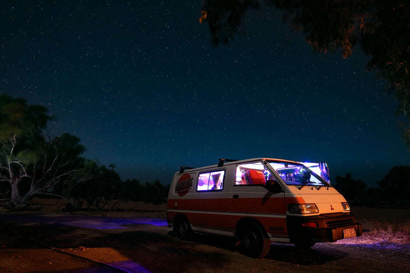 white campervan parked on an empty red dirt road in the outback
