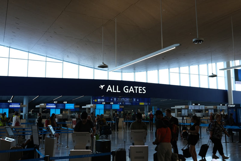 person handing paper receipts and passport across airport counter to staff member