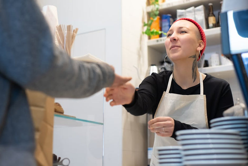 young worker behind counter in Australian cafe serving customer